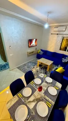a dining room with a table and blue chairs at Mhamid Appartement 3 chambres in Marrakech