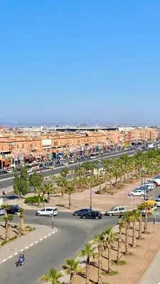 a street with cars and palm trees in a city at Mhamid Appartement 3 chambres in Marrakech