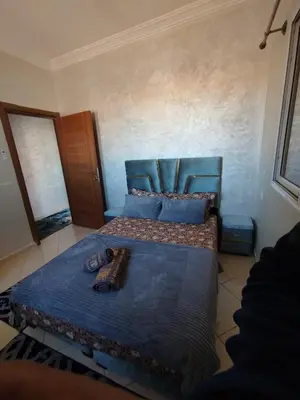 a bedroom with a blue bed with shoes on it at Mhamid Appartement 3 chambres in Marrakech