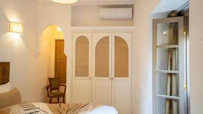 a bedroom with a white cabinet and a chair at Riad Lalla Sofia à 200m des tombeaux Saadiens in Marrakech