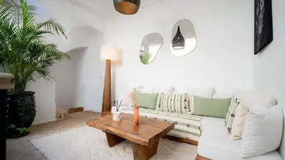 a living room with a white couch and a wooden table at Riad Lalla Sofia à 200m des tombeaux Saadiens in Marrakech