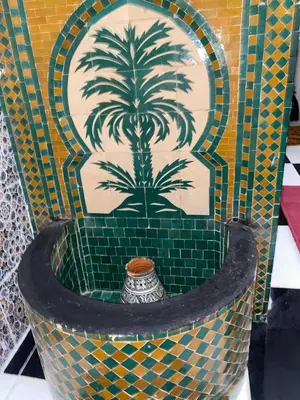 a mosaic fountain with a palm tree on a wall at Riad El yacout in Marrakech