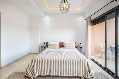 a bedroom with a large bed with striped sheets at Villa Gina, Piscine, Terasse, 15 min du centre in Marrakech