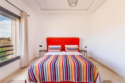 a bedroom with a bed with a red headboard and a window at Villa Gina, Piscine, Terasse, 15 min du centre in Marrakech