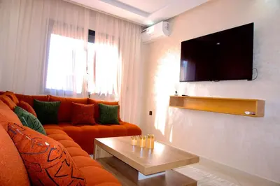 a living room with a orange couch and a flat screen tv at Abir37 in Marrakech