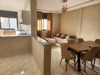 a kitchen and living room with a table and a couch at Appartement Aéroport Holiday in Marrakech