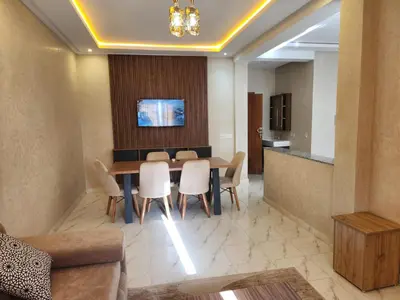 a dining room with a table and white chairs at Appartement Aéroport Holiday in Marrakech