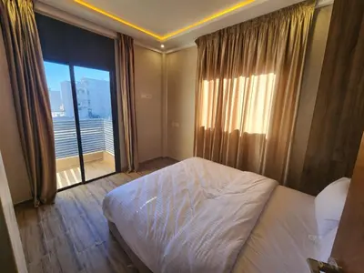 a bedroom with a bed and a large window at Appartement Aéroport Holiday in Marrakech
