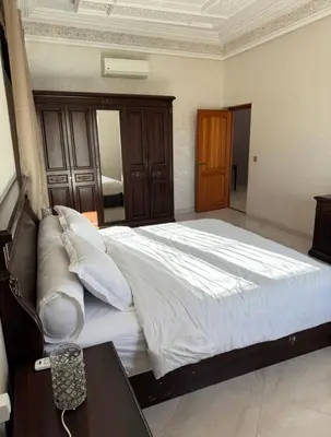 a bedroom with a large white bed and a table at Maison luxueuse méga spacieuse in Marrakech