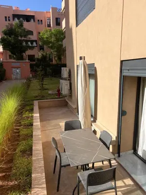 a patio with a table and chairs next to a building at Spacieux duplex 3 chambres - Piscine et parking in Marrakech