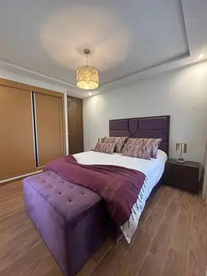 a bedroom with a large bed and a purple ottoman at Spacieux duplex 3 chambres - Piscine et parking in Marrakech