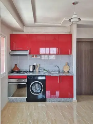 a kitchen with red cabinets and a washing machine at Ilova 1 - Appartement Moderne au Centre de Marrakech in Marrakech