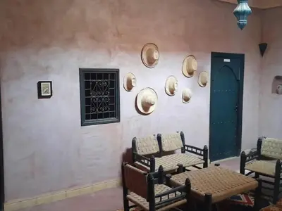 a room with chairs and a wall with hats on the wall at Chants des dunes in Marrakech