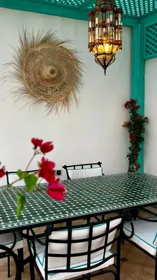 a green table with a red flower and a chandelier at Private - Riad Désiré Marrakech in Marrakech