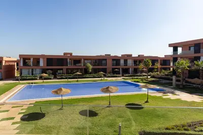a swimming pool in front of a building with umbrellas at Atlas Luxury Escape Golf Noria Pool & Quiet in Marrakech