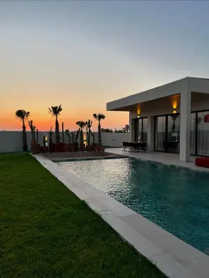 a house with a swimming pool in front of a sunset at Villa Marraktus Marrakech in Marrakech
