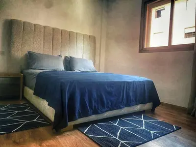 a bedroom with a bed with a blue comforter and a window at Appartement de luxe avec piscine in Marrakech