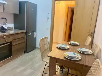 a kitchen with a wooden table with chairs and a table and a table at Appartement de luxe avec piscine in Marrakech