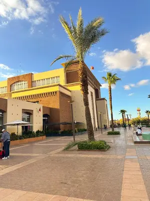 a building with a palm tree in front of it at Stylish 2-bed flat in Marrakech city center - steps from train station in Marrakech