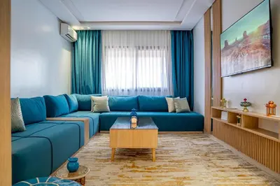 a living room with a blue couch and a table at CAN 2025 - T2 design Gare de Marrakech - Guéliz-Hivernage - WiFi in Marrakech