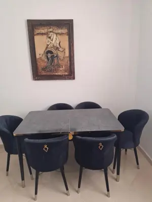 a dining room table with chairs and a painting on the wall at Appartement a louer 2 chambres in Marrakech