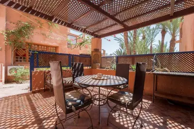 a patio with a table and chairs under a pergola at Traditional, Cozy and Quiet Apartment, Pool, Palmeraie in Marrakech