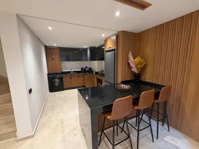 a kitchen with a black table and chairs at Appartement duplex haut standing Guelyz in Marrakech