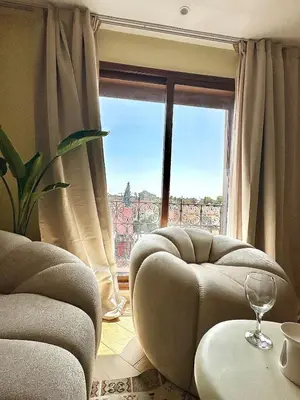 a living room with two chairs and a large window at Downtown Feng Shui-style apartment with mountain view in Marrakech