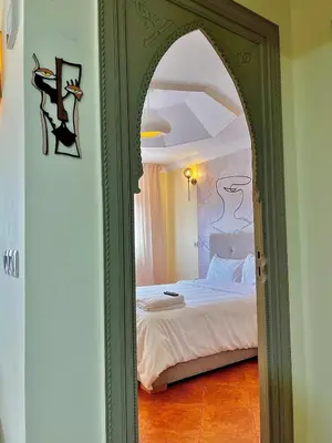 a bedroom with a bed with a green frame and a mirror at Downtown Feng Shui-style apartment with mountain view in Marrakech