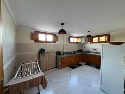 a large kitchen with wooden cabinets and a refrigerator at Le Patio Marrakchi in Marrakech