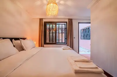 a bedroom with a large white bed with a chandelier at New Luxury Downtown Apart Marrakech 3BR Terraces in Marrakech