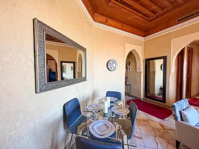 a table with chairs and a mirror on a wall at Oasis Palmeraie - Piscines & terrasses in Marrakech