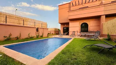 a swimming pool in a yard next to a building at Villa Familiale, Piscine et jardin privés, proche du centre ville in Marrakech