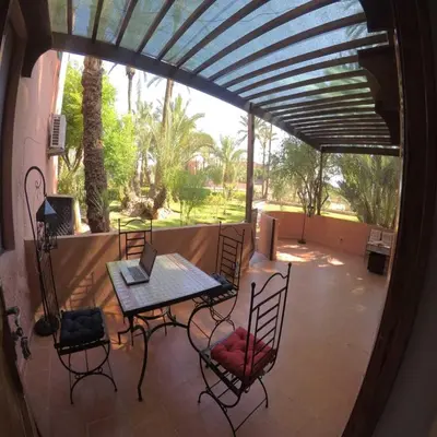 a patio with a table and chairs with a laptop on it at Étoile de marrakech in Marrakech