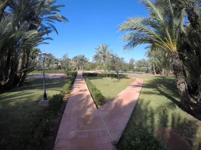a walkway through a park with palm trees at Étoile de marrakech in Marrakech