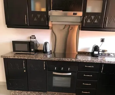 a kitchen with black cabinets and a microwave at Résidence avec piscine &salle de sport a la palmeraie À 10minutes du Madina Marrakech in Marrakech