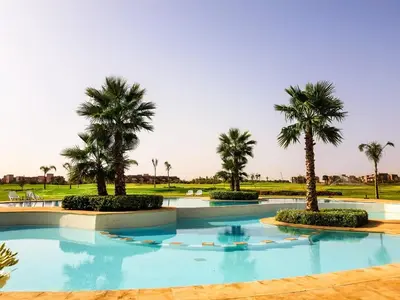 a swimming pool with palm trees in a resort at Luxury Apartments in Marrakech