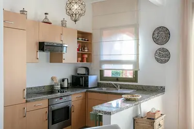 a kitchen with wooden cabinets and a counter top at Marrakech Palmeraie 3, 2-bedroom appartement, ,res with pool in Marrakech