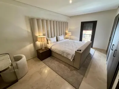 a bedroom with a bed with two lamps and a chair at Modern apartment in Gueliz Plaza in Marrakech