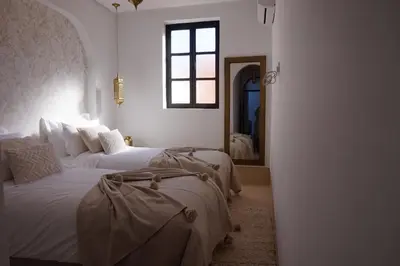 a bedroom with two beds and a window and a mirror at Little date in Marrakech