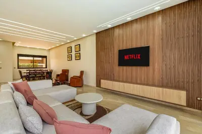 a living room with couches and a tv on a wall at Golf Resort 4BR Villa Heated Pool Free Pickup in Marrakech