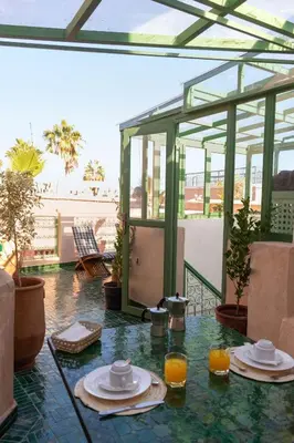 a glass table with two plates of food on a patio at Riad Dar 77 in der Medina mit Terrasse in Marrakech