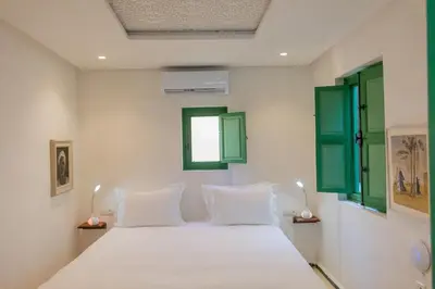 a bedroom with a white bed with green windows at Riad Dar 77 in der Medina mit Terrasse in Marrakech