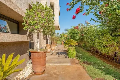 a walkway with potted trees in pots next to a building at Modern Golf Retreat Heated Pool & Free breakfast in Marrakech