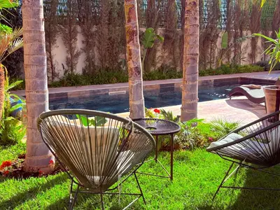 two chairs and a table next to a swimming pool at Palais Naya in Marrakech