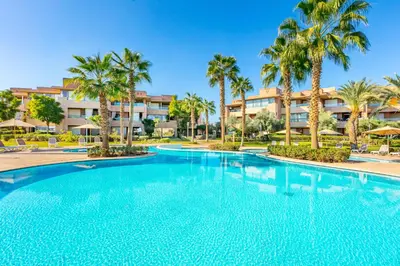 a large swimming pool with palm trees in front of a building at Golf View Escape in Oulad Akkou