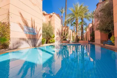a swimming pool in a resort with palm trees at New Stylish Riad - 4BR with Pool Access Free Breakfast & Airport Pickup in Marrakech