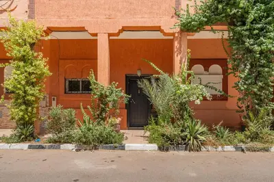 an orange building with a black door and some plants at New Stylish Riad - 4BR with Pool Access Free Breakfast & Airport Pickup in Marrakech