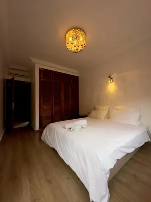 a bedroom with a large white bed with a chandelier at Luxury 2 bedroom apartment - Gueliz Plaza in Marrakech