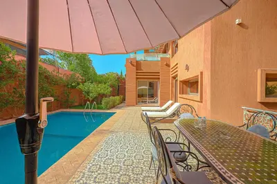 a table and chairs with an umbrella next to a pool at Villa Andalus - Piscine privée & Suite Parentale in Marrakech